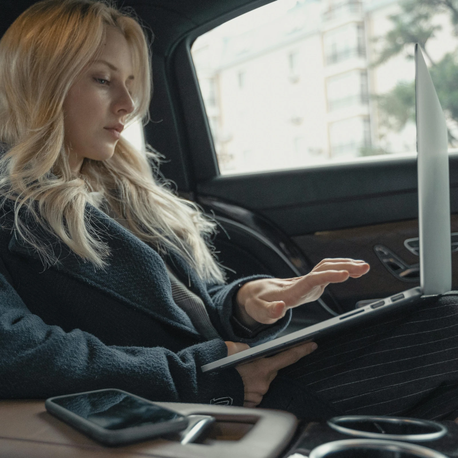 Executive working on a laptop in the back seat of a Lux Chauffeur electric business car